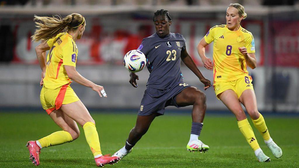 England's Michelle Agyemang controlling the ball with two Belgian players surrounding her.