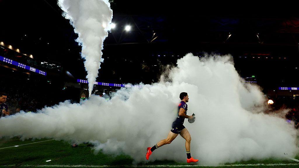 NRL player running on to the field with smoke billowing behind him in a match in Brisbane, Australia on 4 May 2025.