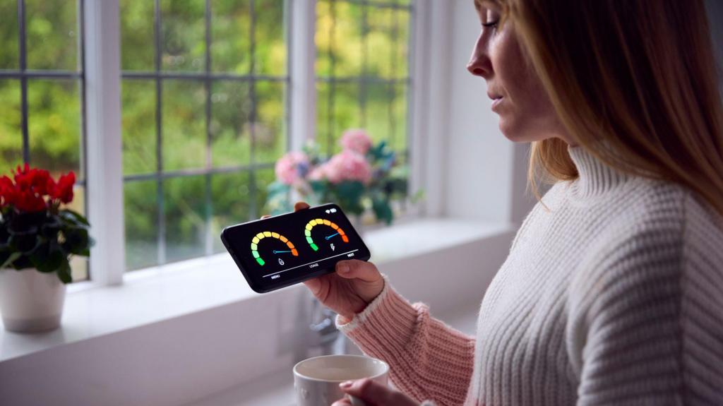 Worried Woman Looking At Smart Meter In Kitchen At Home During Cost Of Living Energy Crisis