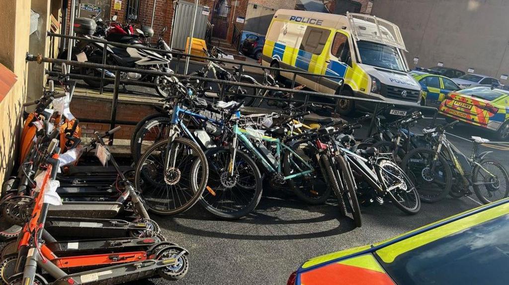 Piles of bikes and scooters outside a police station