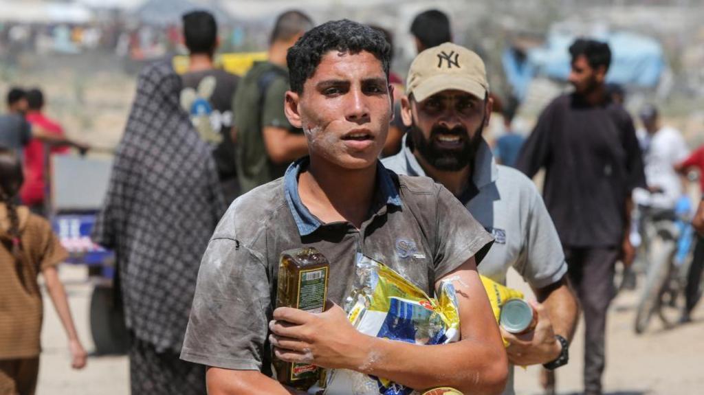 Palestinians collect aid parcels that were airdropped, amid a hunger crisis, in Zawayda, in the central Gaza Strip, July 31, 2025.