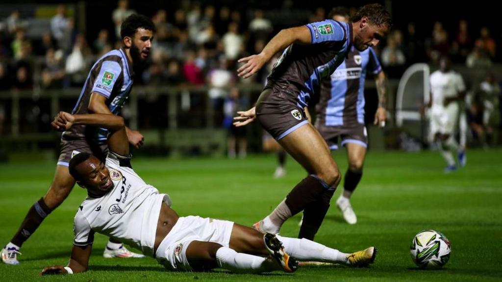 Marcus Dinanga of Bromley is being pulled off the ball during the Carabao Cup match between Bromley and AFC Wimbledon