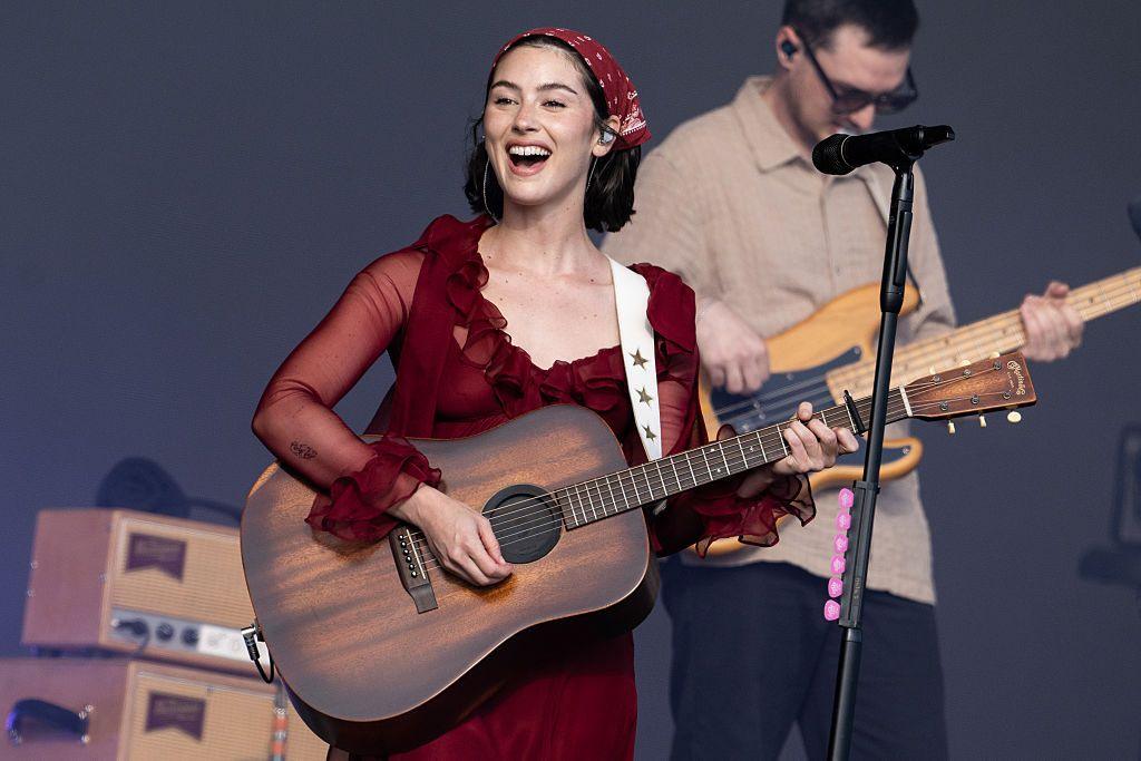 Gracie Abrams plays a walnut-effect acoustic guitar during a concert in 2025