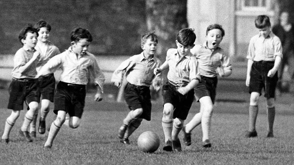 Prince Charles plays football at school with class mates. 