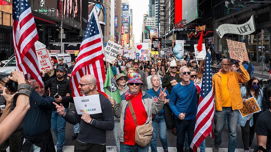 protesters waving signs and flags in NYC streets