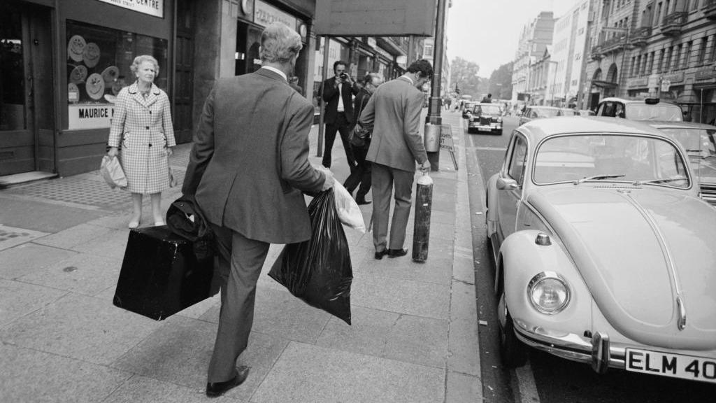 Plain clothes police walking on Baker Street in an archive image. They carry black plastic bags and evidence boxes