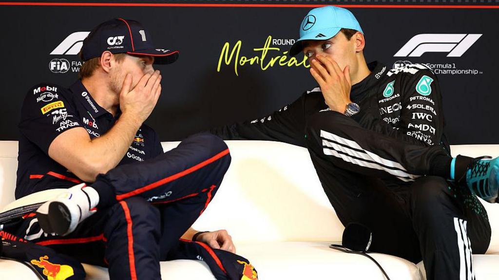 With hands covering their mouths, Max Verstappen and George Russell speak to each other during a news conference at the Canadian Grand Prix