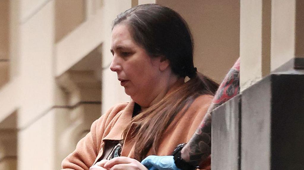 Murder convict Erin Patterson wearing brown and emerging from a court house