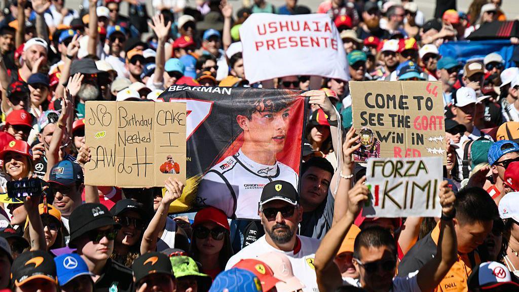 Fans hold up signs for drivers in the Barcelona fan zone 