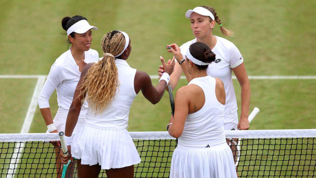 Su-Wei Hsieh, Elise Mertens, Coco Gauff and Jessica Pegula shaking hands at the net, all wearing white.