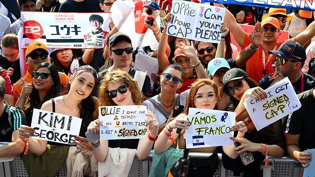 Fans hold up signs in the Qatar paddock