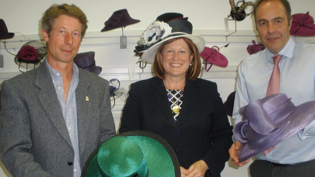 Helen Nellis wearing a hat standing next to two men