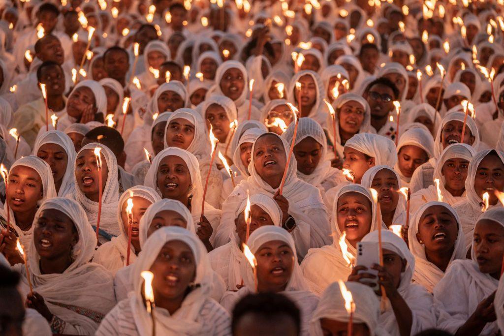 Worshippers hold candles and sing religious hymns as they gather for the eve of Ethiopian Orthodox Christmas celebrations at Bole Medhanialem Church in Addis Ababa on January 6, 2025. 