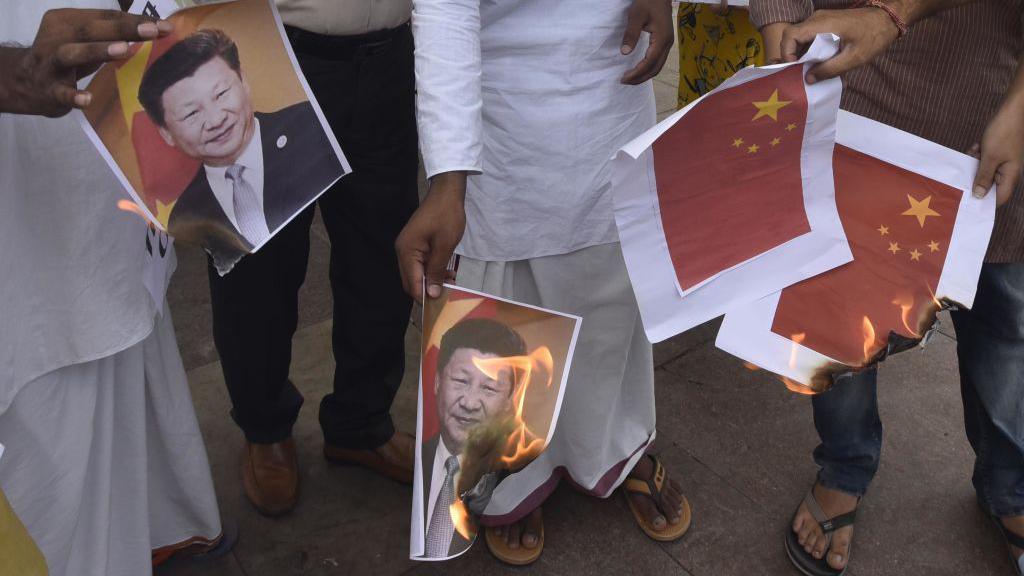 File picture from 2020 showing men in New Delhi wearing white kurtas, jeans and shirts burning print-outs of Xi Jinping's portrait and the Chinese flag