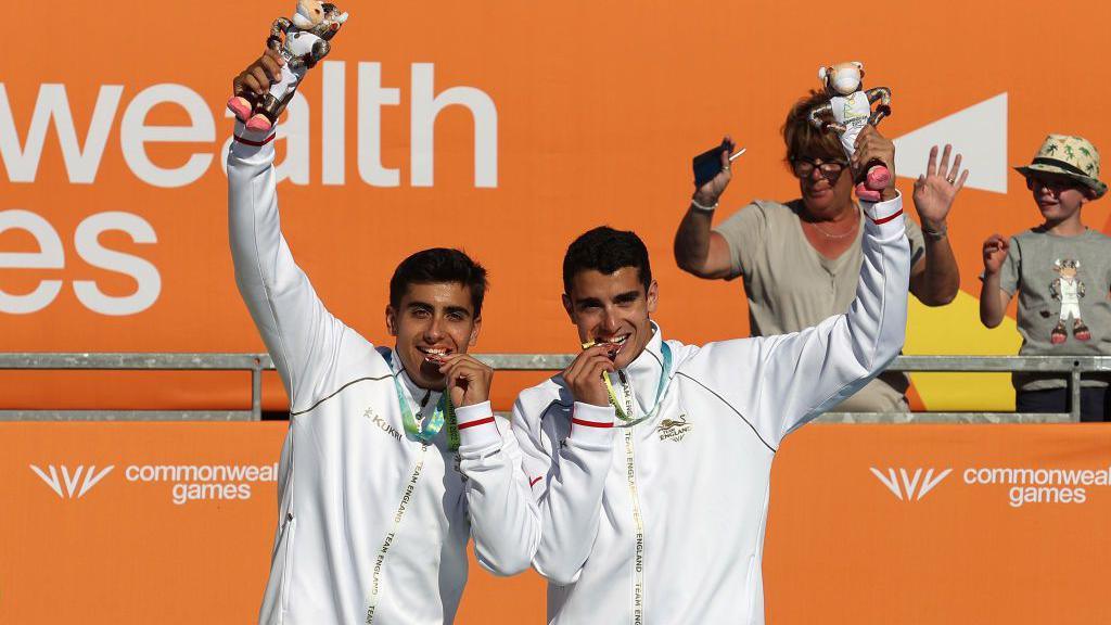 Javier [left] and Joaquin Bello bite their bronze medals and hold their prizes aloft at the Commonwealth Games