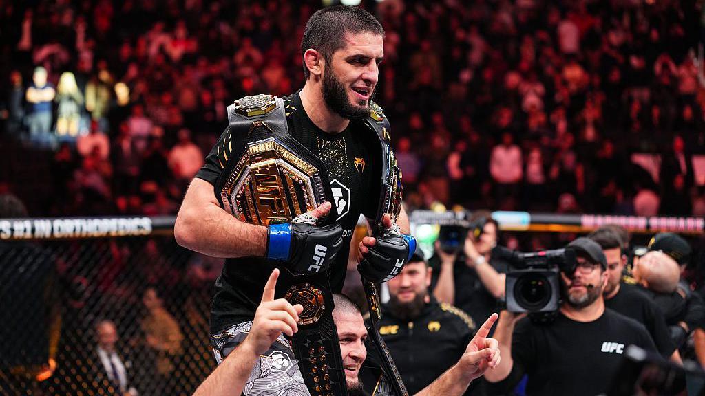 Islam Makhachev celebrating on the shoulders of Khabib Nurmagomedov