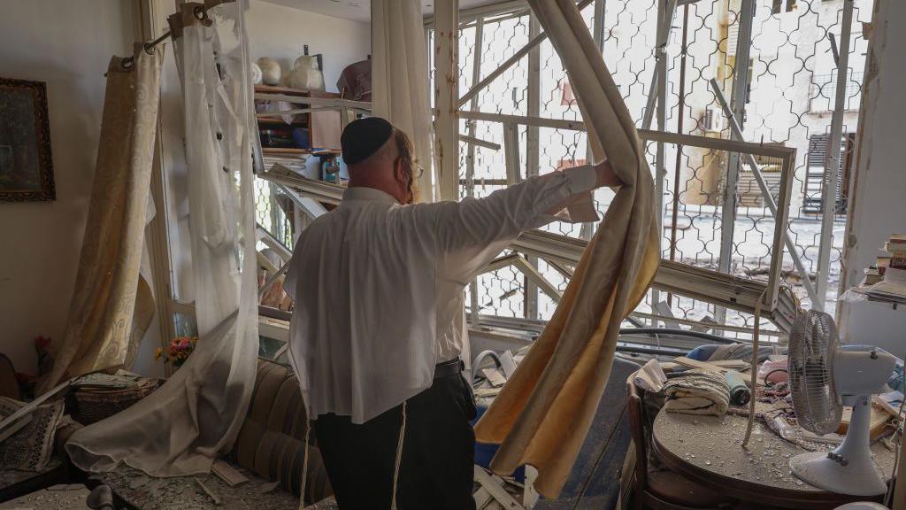 A man inspects an apartment which was damaged by a rocket fired by Hezbollah from Lebanon, in Kiryat Yam, near Israel's northern city of Haifa (8 October 2024)