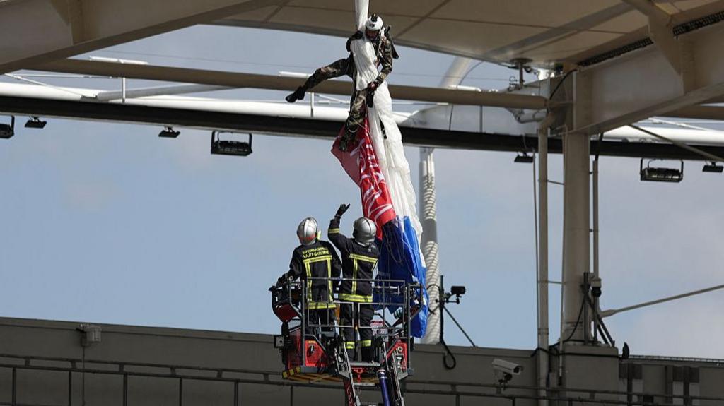 Sale game delayed as parachutist hangs from roof