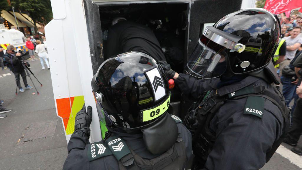 Riot police stood behind police land rover in Belfast city centre