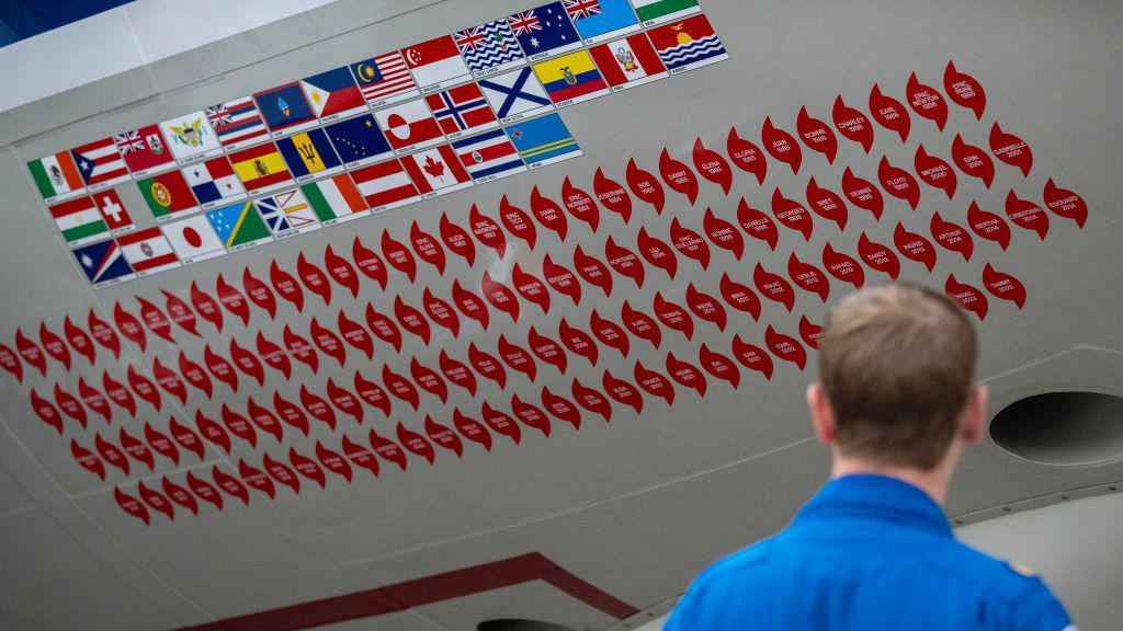 Stickers of previous hurricane missions adorn the side of an NOAA  WP-3D Orion hurricane hunter aircraft, nicknamed "Kermit," in 2024.