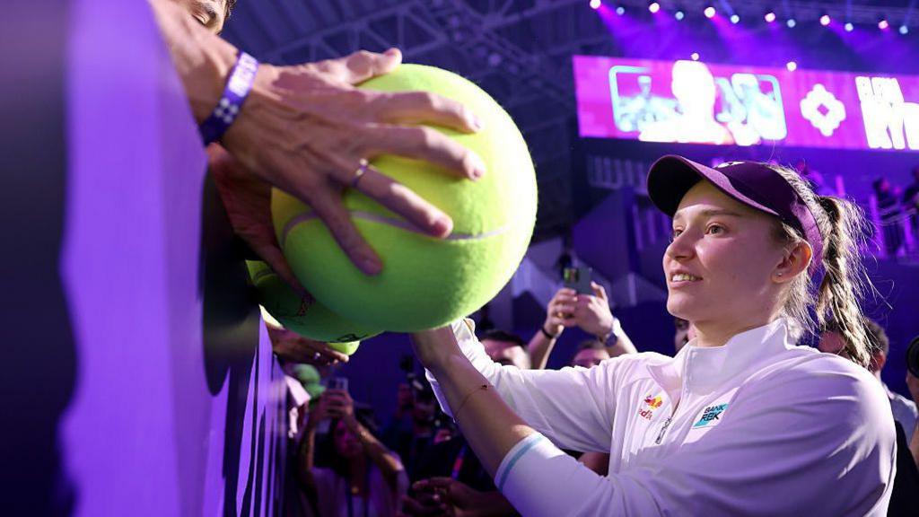 Elena Rybakina goes to sign a giant tennis ball for a fan