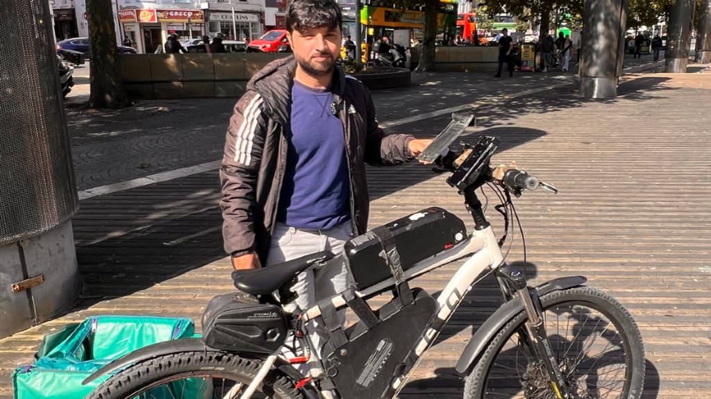 A delivery rider holding his converted e bike - which holds a motor, battery and wires.