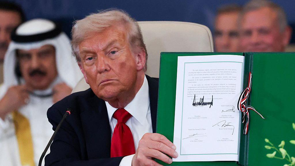 Trump holds up an agreement.