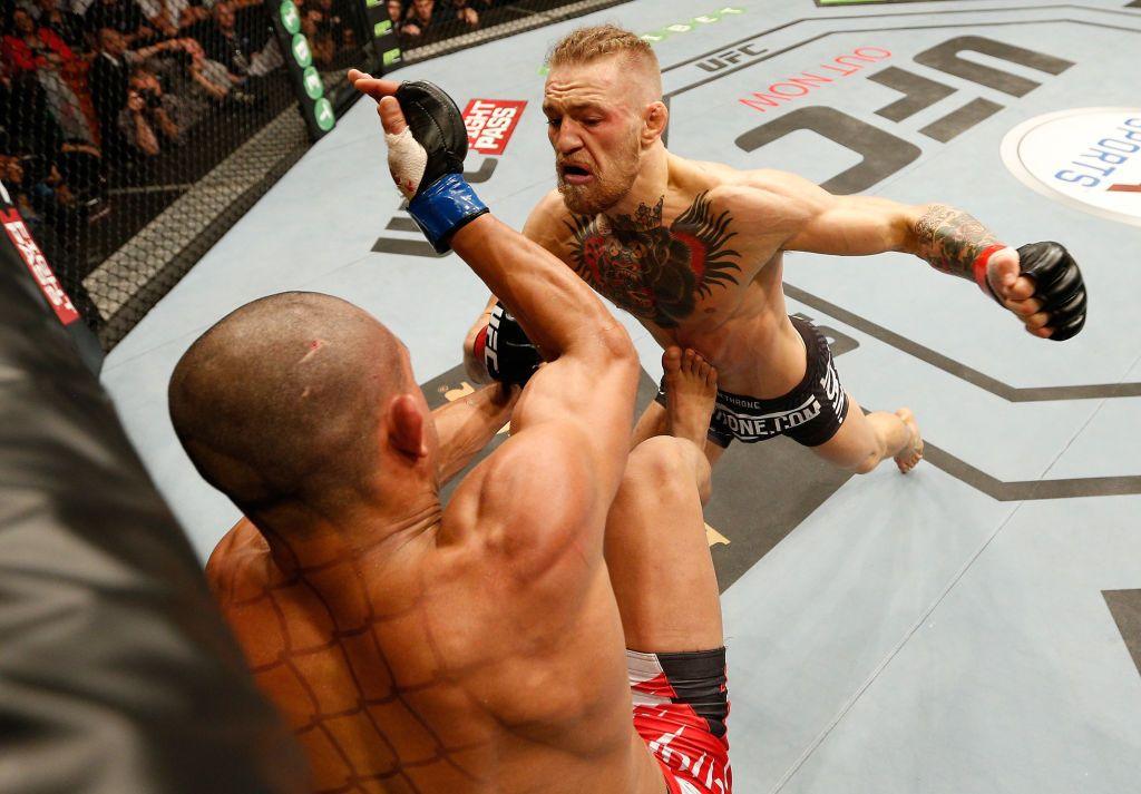 Conor McGregor, in trunks, lifts his left fist to prepare to punch Diego Brandao, also in trunks, during a UFC fight