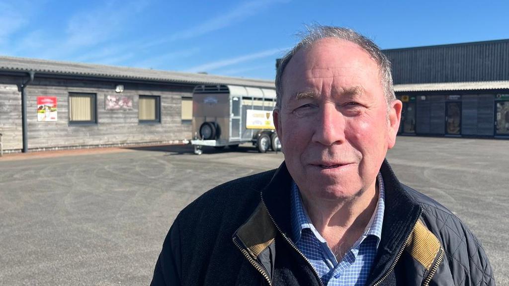 Ken James, leader of Torridge District Council, in a blue check shirt, a blue zip-up jumper and a blue coat, at Holsworthy Market