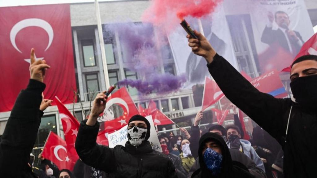 Protesters use red and purple flames - one of the young-looking protesters is wearing a face mask with a skeleton design