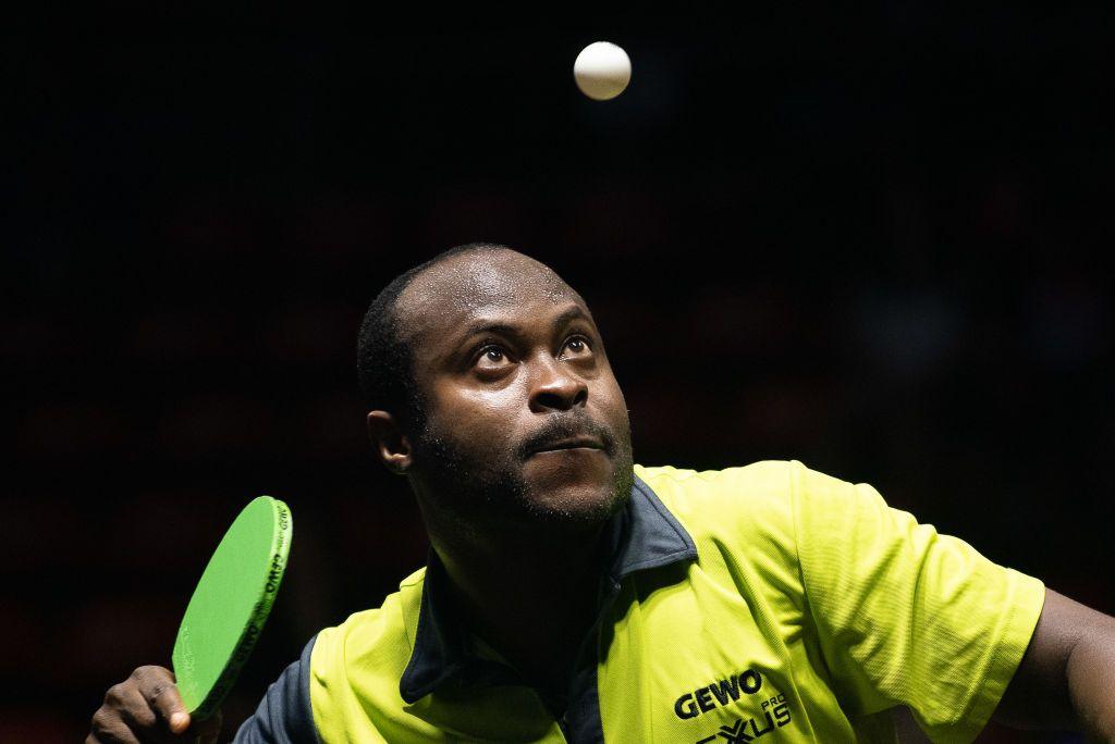 A man focuses intently on a table tennis ball in the air just above his head.