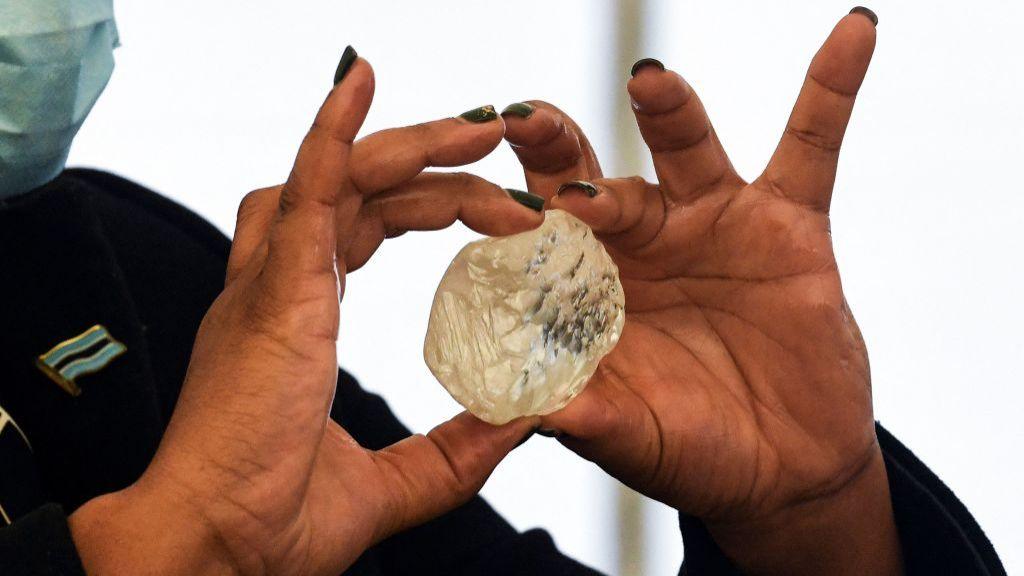 A woman with painted nails holds a large diamond