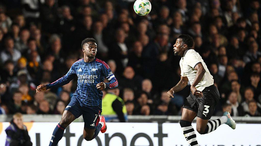 Arsenal's Bukayo Saka challenges for a high ball against Port Vale's Jaheim Headley
