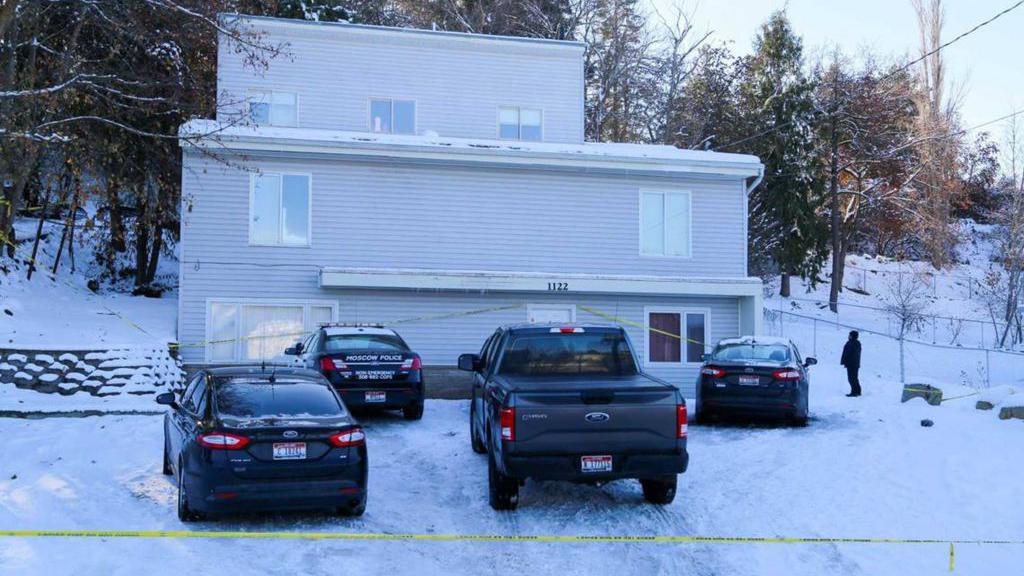 House with cars outside parked on snowy ground is taped off by yellow police tape