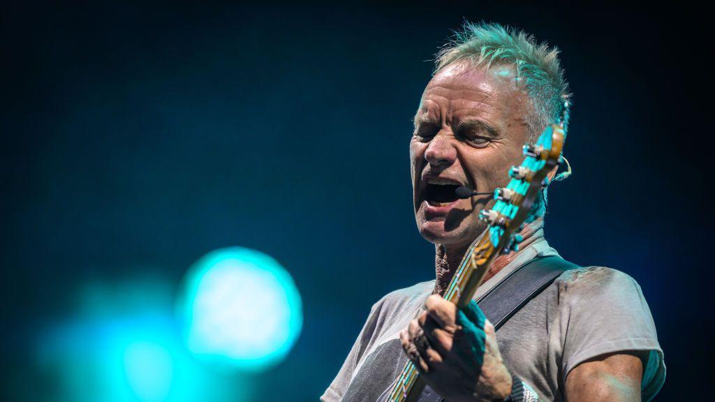 Sting is pictured singing on stage while playing the guitar during Radio 2 Live in the Park at Moor Park, Preston in September 2024.