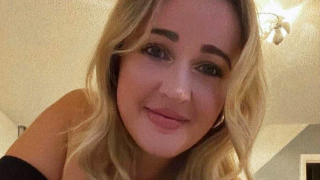 Laura has curly blond hair and is looking into camera with a slight smile