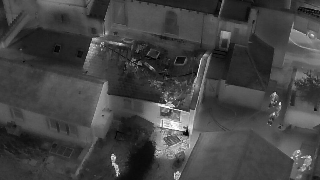 Aerial view of crews dealing with fire in a classroom. Black and white images. show the building on the left with some firefighters inside the classroom and two groups of three outside. 