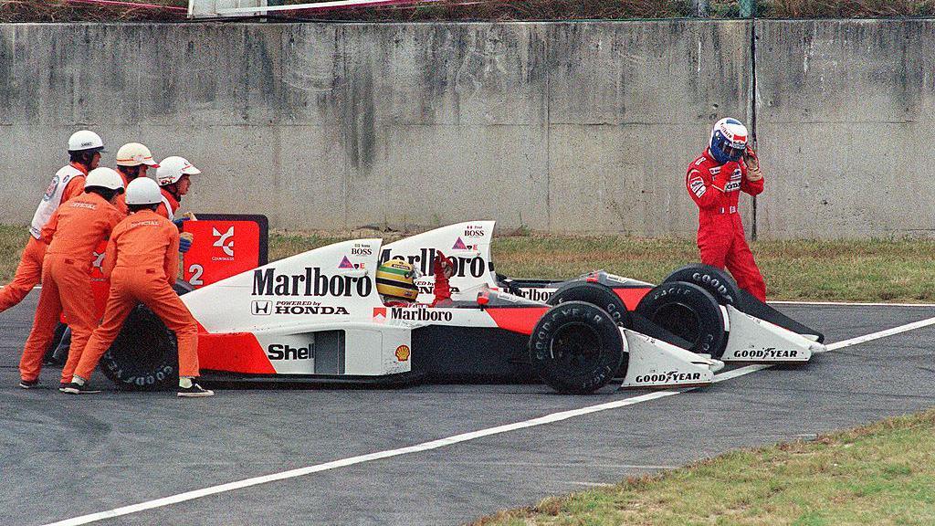 Ayrton Senna is given a push from circuit marshals for a restart while his team-mate and bitter rival Alain Prost leaves his car to abandon the race after the two collided in a chicane during the Japan Grand Prix in Suzuka