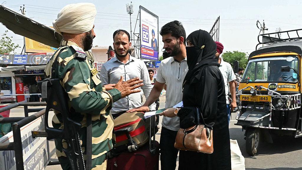 An Indian Border Security Force (BSF) personnel (L) inspects passports and documents of a Pakistani citizen (R) accompanied by her husband, an Indian citizen, as she prepares to return to her country through the India-Pakistan Wagah border post, about 35kms from Amritsar on on April 29, 2025.