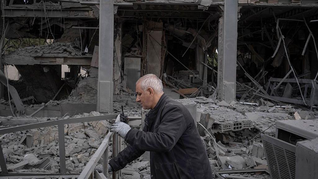 A man searches through the rubble of a bombed building.