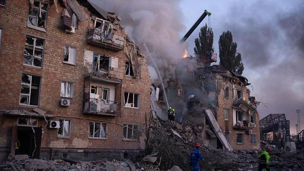 A residential building is partially destroyed and has smoke coming out the top of it