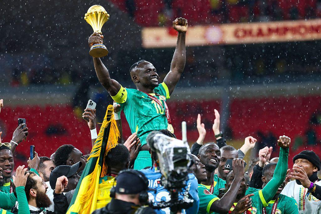 Senegal players, including forward Sadio Mane who is held up by other players, celebrates by lifting the trophy high in the air after the game
