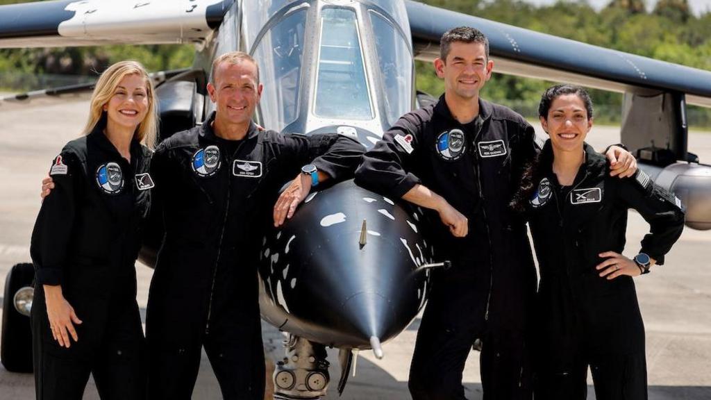 Four people in NASA suits standing by a plane