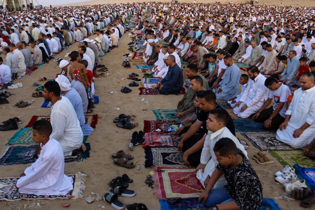 Hundreds of people praying outside on mats