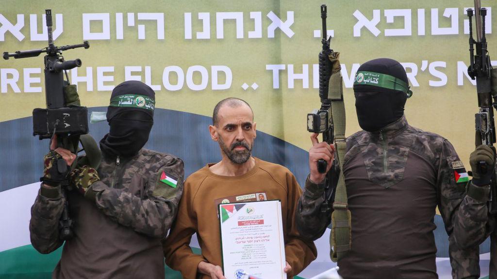 Hamas fighters escort Israeli hostage Eli Sharabi to a stage before handing him over to a Red Cross team in Deir el-Balah, central Gaza, on 8 February