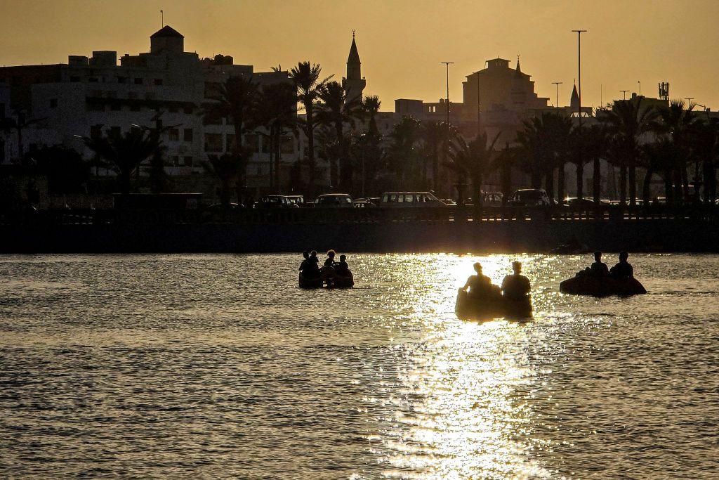 People sit in boats in the artificial Saraya Museum Lake by the Martyrs' Square. The sun is setting behind them.