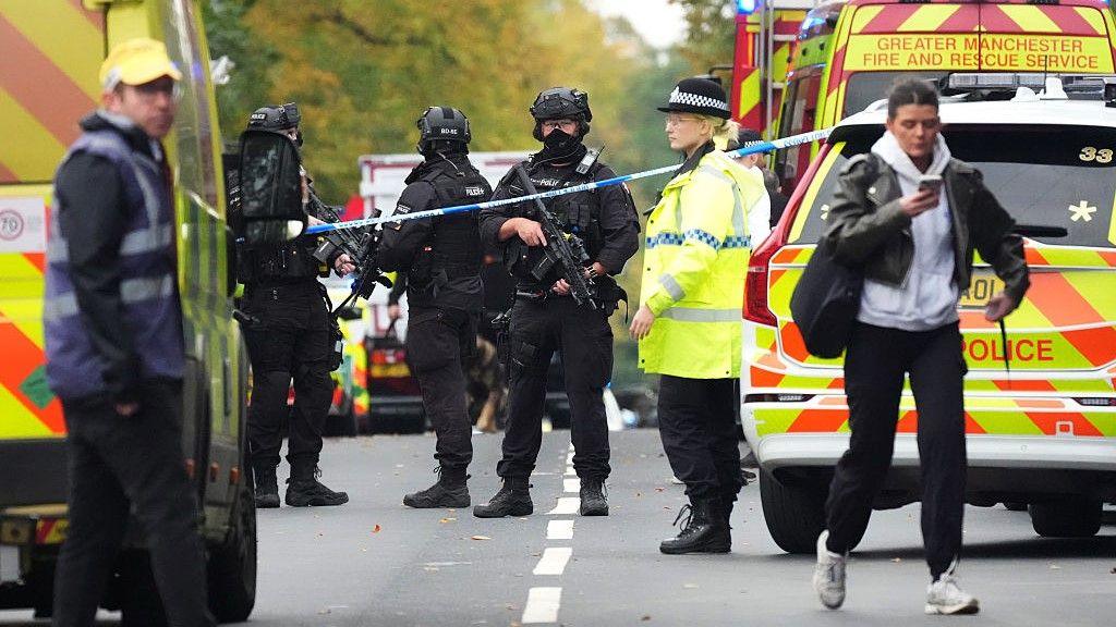 Armed Police, emergency responders and congregants gather near the Heaton Park Hebrew Congregation Synagogue 