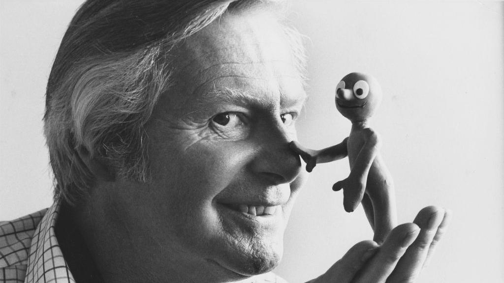 Tony Hart holding a Morph that is touching his nose.