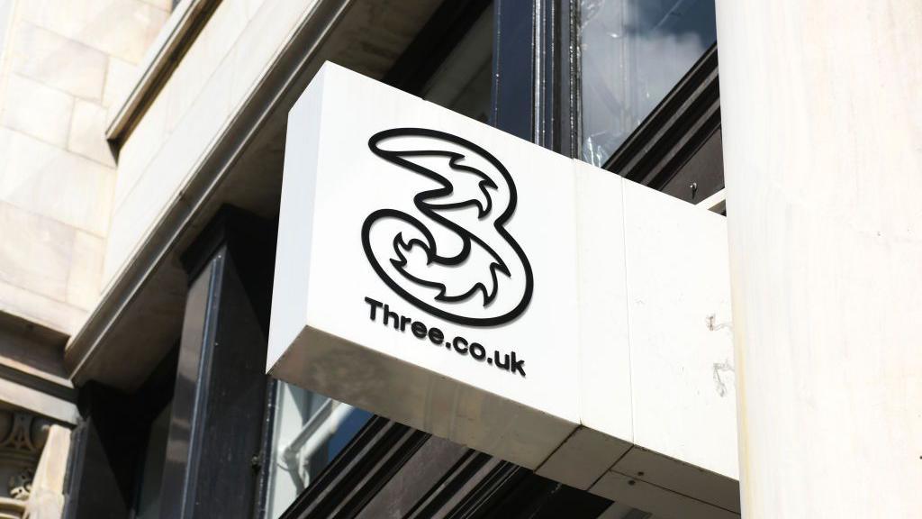 A white shop sign with the Three logo on it.