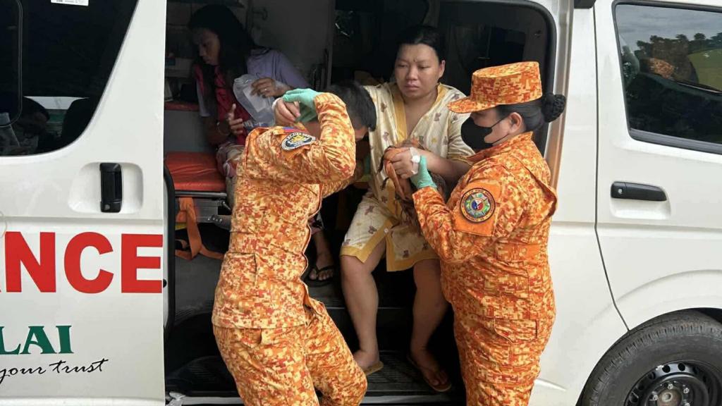 A woman is helped out of an ambulance by two members of the Philippines fire service  